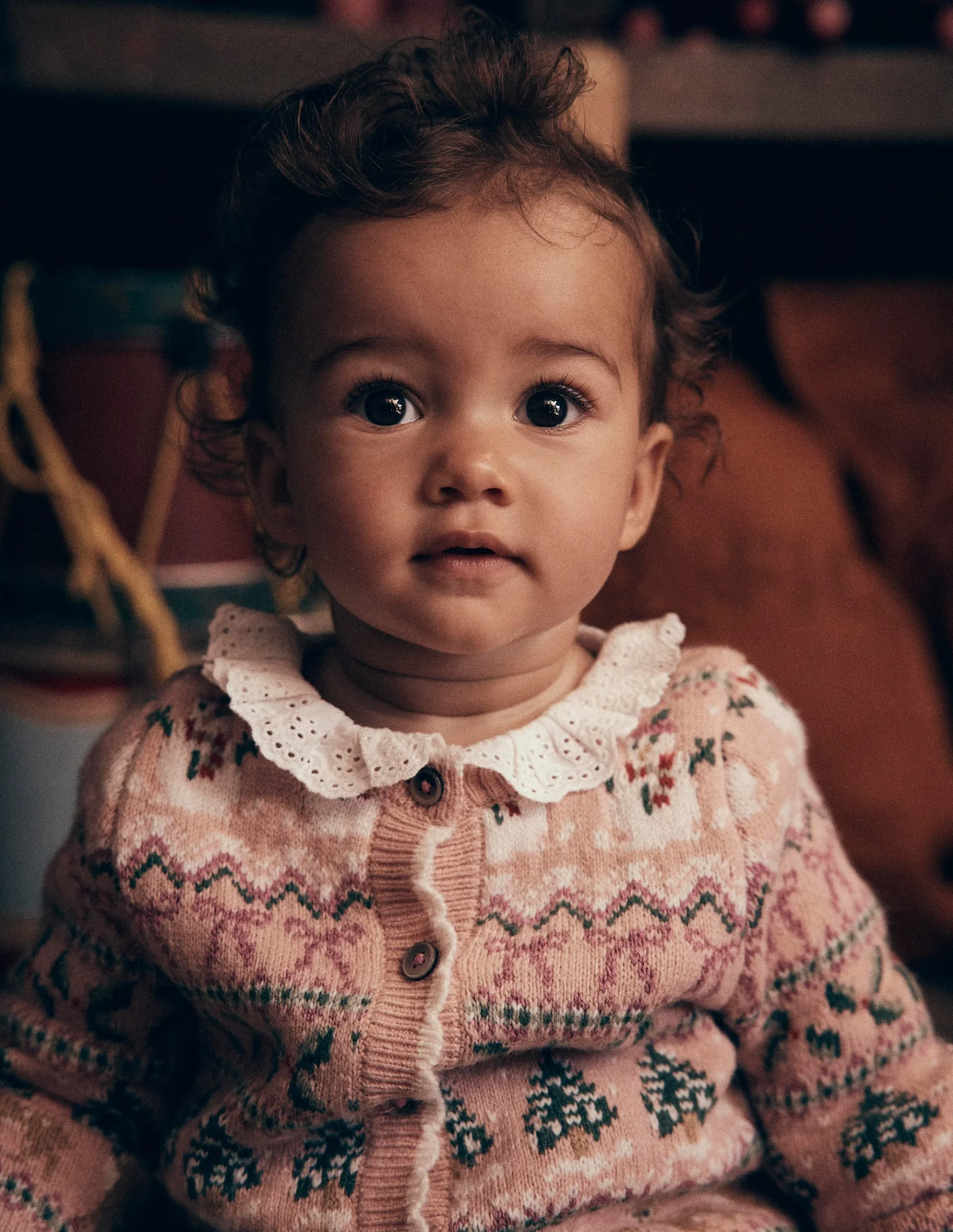 Baby in a pink Fair Isle cardigan with a broderie collar, Mini Boden Polar Post Winter 2026